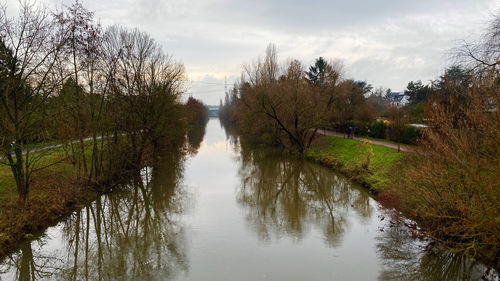 Reflection of trees in canal against sky