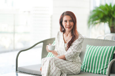 Portrait of a smiling young woman drinking coffee