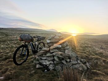 Bicycle on mountain against sky during sunset