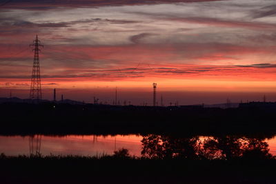 Silhouette electricity pylon against sky during sunset