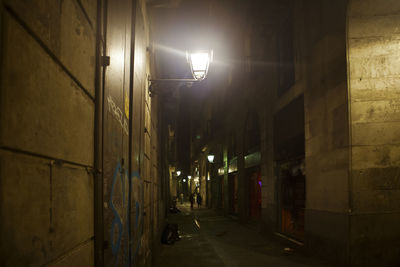 Illuminated street amidst buildings at night