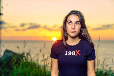 Young woman standing at beach during sunset