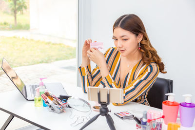 Young woman vlogging on table in office