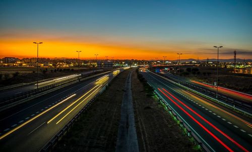 Light trails on road in city against sky at night