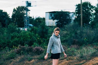 Girl standing by plants against trees