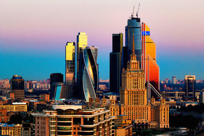 Skyscrapers in city at sunset