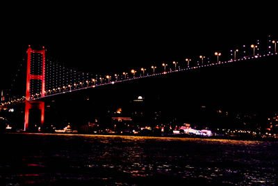 Illuminated bridge over river at night