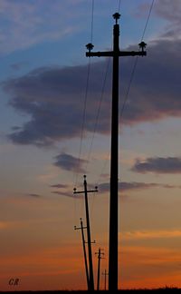 Low angle view of power lines against cloudy sky