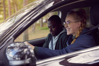 Smiling woman driving car while sitting with man