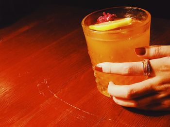 Close-up of hand holding drink on table