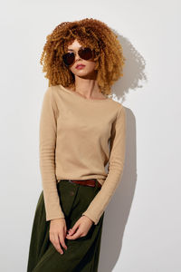 Portrait of young woman standing against white background