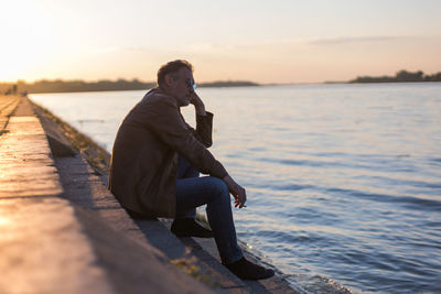 Lonely man sitting on stairs next to the river bank