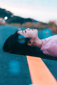 Side view of thoughtful woman lying on road
