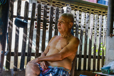 Shirtless senior man sitting indoors