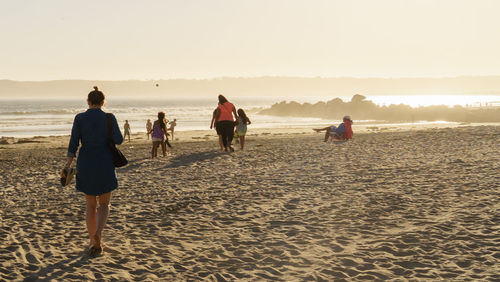 People on beach against sky during sunset