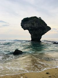 Rock formation on beach against sky