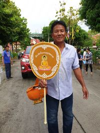 Portrait of smiling man holding umbrella standing on street