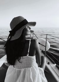 Rear view of woman sitting on boat against sea