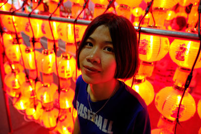 Portrait of smiling woman standing against illuminated lanterns at night