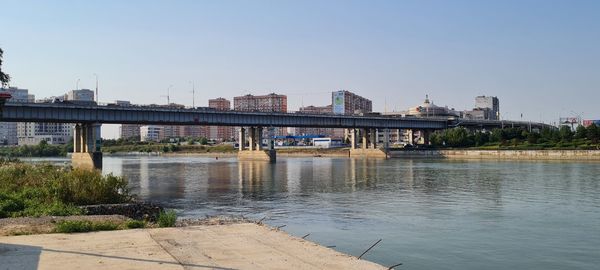 Bridge over river in city against clear sky