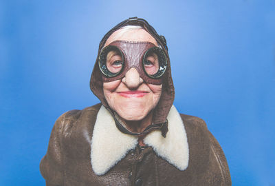 Portrait of senior woman wearing costume standing against blue background