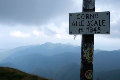 Information sign on mountain against sky