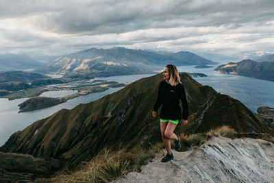 Full length of woman standing on rock against sky