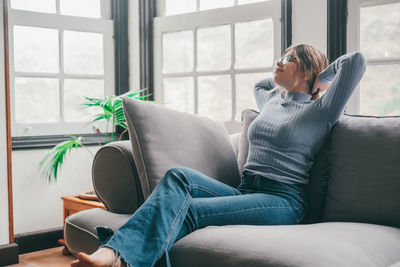 Young woman using laptop while sitting on sofa at home