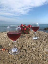 Wineglass on beach by sea against sky