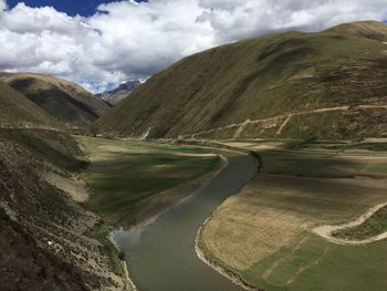 Scenic view of river by mountains against sky