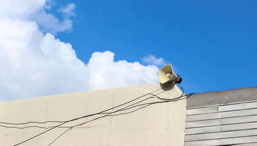 Low angle view of microphone on building against sky