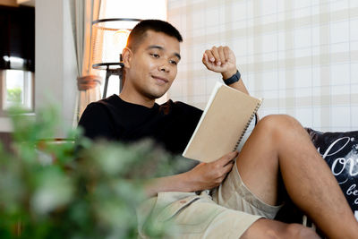 Young man looking away while sitting at home