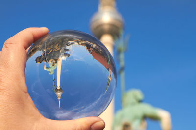 Cropped hand holding crystal ball against fernsehturm