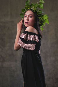 Portrait of beautiful young woman standing against plants