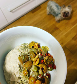 A bowl with tuna paste and sliced olives, capers, dog in the background, homemade, yorkshire terrier