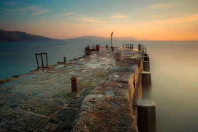 Pier over sea against sky during sunset