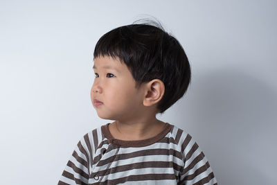 Cute boy looking away against white background