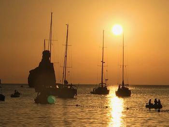 Silhouette sailboats in sea against sky during sunset