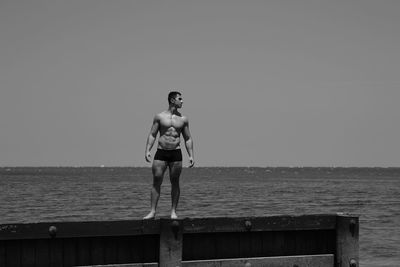 Man standing on pier over sea against clear sky