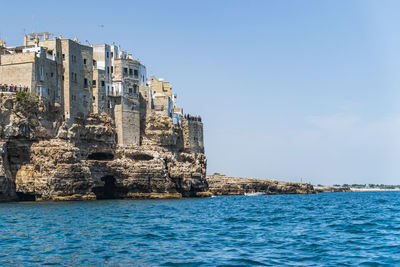 Sea by buildings against sky