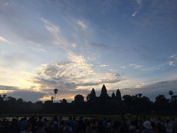 People at temple against sky during sunset