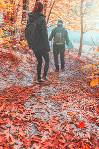 Rear view of people walking on leaves during autumn