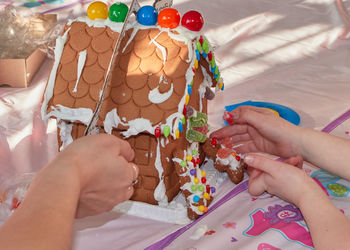 Mom and daughter making a gingerbread house on christmas day