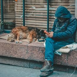 Poor man with dog sitting against window