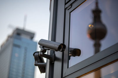 Low angle view of security camera on building against sky during sunset