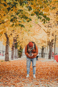 Full length of woman standing with autumn leaves