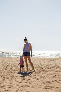 Woman walks with her little son on a sandy beach near the sea in the summer