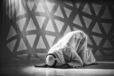 Man sitting on floor against wall