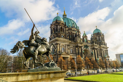 Statue and historic building against sky