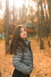 Young woman standing against trees